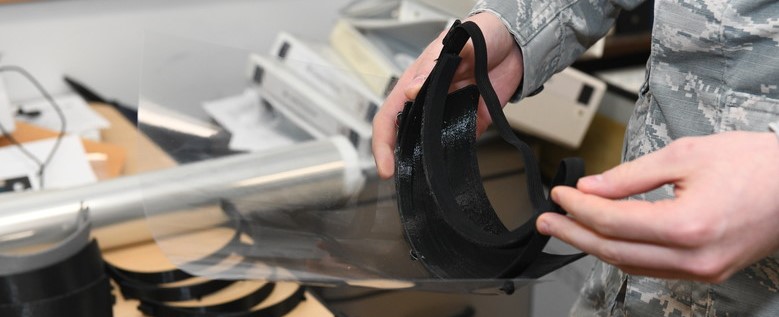 Hands holding COVID face shield with VELCRO